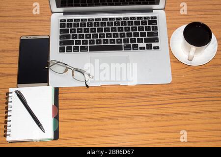 Desk with open notebook, mobile phone, eye glasses, pen and a cup of coffee. Top view with copy space. Business still life concept with office stuff o Stock Photo