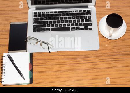 Desk with open notebook, mobile phone, eye glasses, pen and a cup of coffee. Top view with copy space. Business still life concept with office stuff o Stock Photo