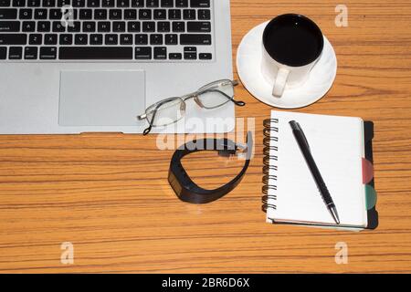 Desk with open notebook, wrist watch, eye glasses, pen and a cup of coffee. Top view with copy space. Business still life concept with office stuff on Stock Photo