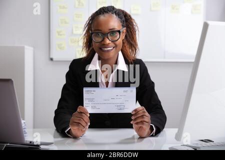 Close-up Of A Smiling Businesswoman Showing Company Cheque Stock Photo