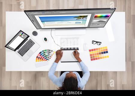 Young Female Designer Editing Photos On Computer In Office Stock Photo