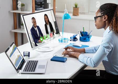 African Businesswoman Analyzing Graphs While Videoconferencing With Her Colleagues In Office Stock Photo