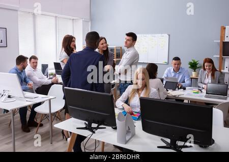 Group Of Businesspeople Discussing Together With His Colleague Working In The Office Stock Photo