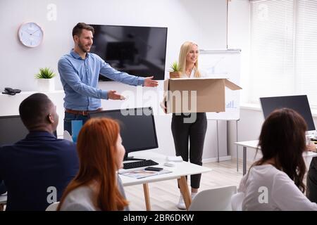 Smiling Young Manager Welcoming New Female Employee Introducing Her To Old Colleagues At Workplace Stock Photo