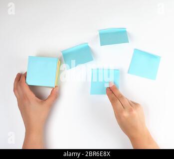 lot of empty blue stickers on a white background and two female hands, conceptual background Stock Photo