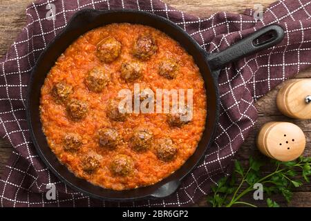 Homemade beef meatballs in fresh tomato sauce in cast-iron skillet, photographed overhead Stock Photo