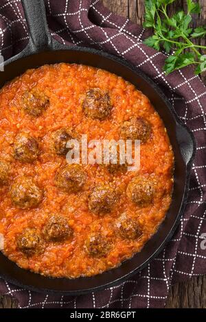 Homemade beef meatballs in fresh tomato sauce in cast-iron skillet, photographed overhead Stock Photo
