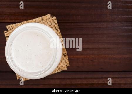 Fresh homemade bubbly sourdough starter, a fermented mixture of water and flour to use as leaven for bread baking, in glass jar, photographed overhead Stock Photo