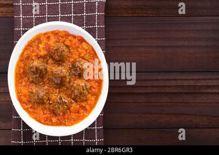 Homemade beef meatballs in fresh tomato sauce in bowl, photographed overhead with copy space on the side Stock Photo