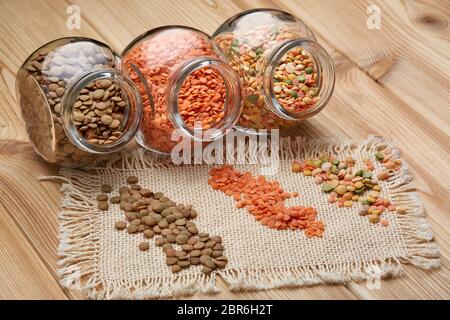 Various types of dry lentils  in glass jars lying on wooden background. Different kinds legumes. Stock Photo