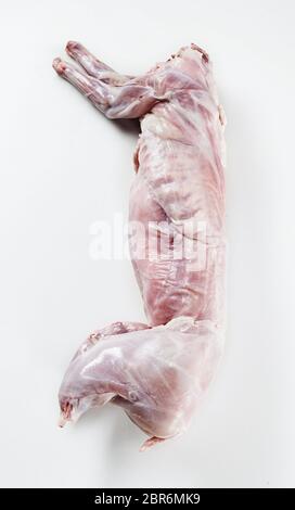 Cleaned skinned wild rabbit carcass ready for roasting lying on a white background viewed from above in vertical format Stock Photo