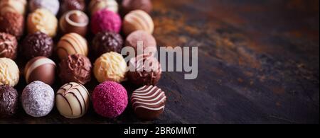 Panorama banner of assorted decorative handmade luxury chocolate balls on textured rustic or vintage wood with copy space Stock Photo
