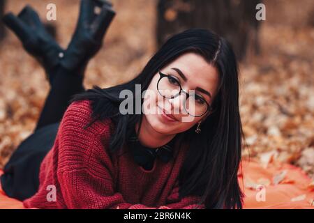 Girl lying on the plaid in autumn forest, nature background. Stock Photo