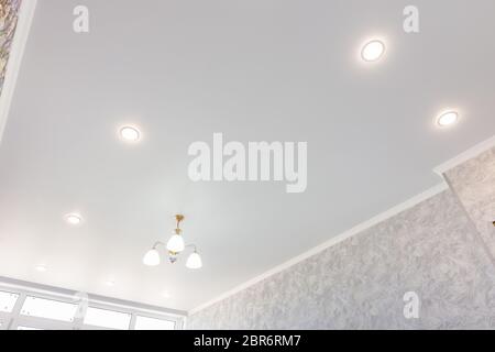 Stretch ceiling in the room with a chandelier and spotlights Stock Photo