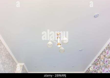 Stretch matte ceiling in the room with a chandelier and spotlights, with natural light Stock Photo