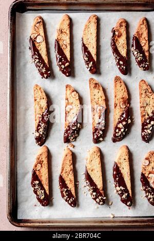 Rows of chocolate dipped hazelnut biscotti on a baking tray. Stock Photo