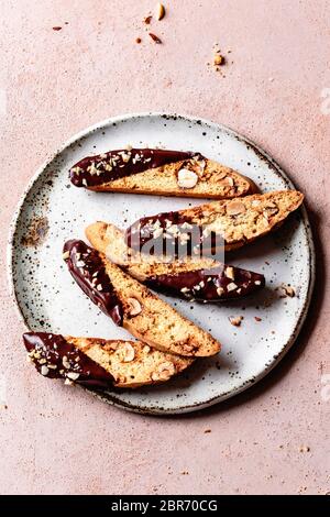 Pieces of chocolate dipped hazelnut biscotti on a ceramic plate. Stock Photo