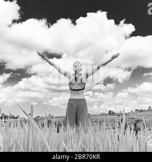 Relaxed healthy woman, arms rised, enjoying pure nature at beautiful green rice fields on Bali. Concept of healthy and clean environment, ecology, bal Stock Photo