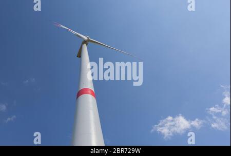 Wind turbine view with blades spinning around under a beautiful blue cloudy sky Stock Photo