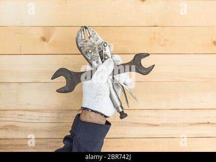 Working hand in glove holding a Spanner and Adjustable wrench with wall wood background Stock Photo