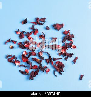 Pile of dry hibiscus karkade herbal tea on blue background, top view. Stock Photo