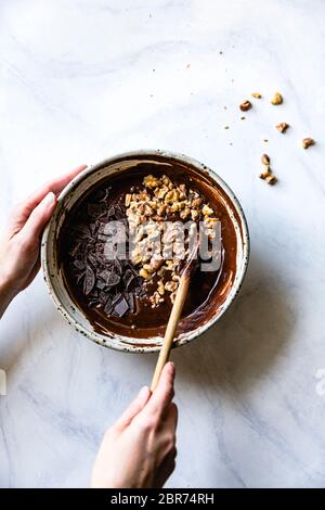 Stirring walnuts and chocolate into brownie batter. Stock Photo