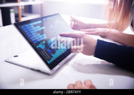 Close-up Businessman's Hand Pointing Bar Graph On Laptop Screen Over White Desk At Workplace Stock Photo