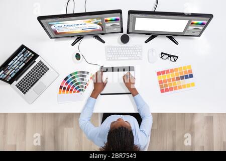 Young Female Designer Editing Photos On Computer In Office Stock Photo