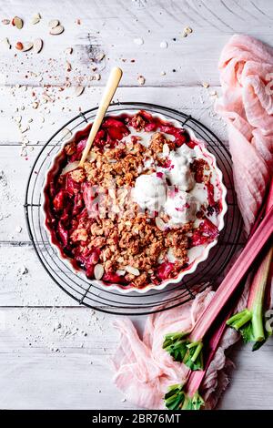 Rhubarb crisp in a baking dish beside fresh rhubarb stalks. Stock Photo