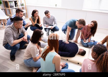 Male Specialist Performing Massage On Man During Training Stock Photo