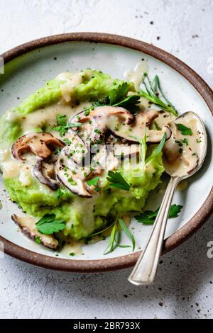 Partial view of green mashed potatoes with mushroom gravy on a ceramic plate. Stock Photo