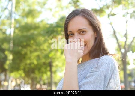 Timid adult woman posing looking at you standing in a park Stock Photo