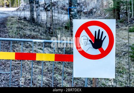 Close up photo of warning sign - no entry to restricted area. The sign hangs on metal fence, forest at background. Prohibited, restricted area for peo Stock Photo