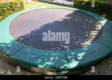 Green trampoline on the lawn in garden close-up empty children toys Stock Photo