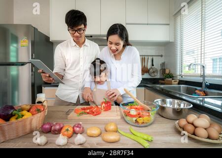 Asian mother teaching cutting vegetable to daughters and father stand by when a family cooking in the kitchen at home. Family life love relationship, Stock Photo