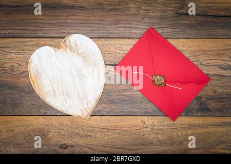 Retro classic Valentines Day cad, large white painted wooden hart, isolated, red envelope with wax seal, on vintage oak panels, top view Stock Photo