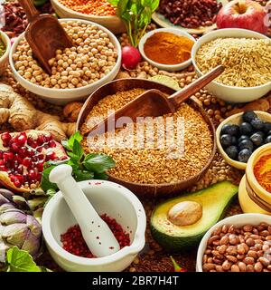 Mulitple bowls filled with different kinds seeds and legumes and surrounded by various herbs ginger and avacado Stock Photo