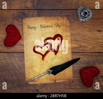 Antique preachment with written Happy Valentines Day, 2 red cuddle hearts, painted hearts, detailed silver quill stand in shape of hart, ornamented si Stock Photo