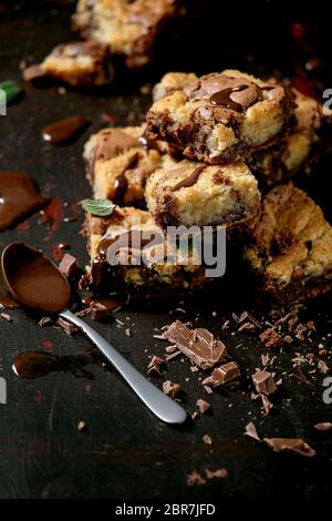 Trend baking Brookies chocolate brownies and cookies homemade cake sliced by squares in row, chocolate sauce, mint on black background. Stock Photo