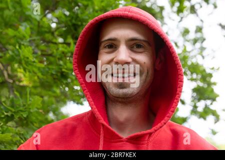 Portrait from young handsome guy wearing a red hood Stock Photo