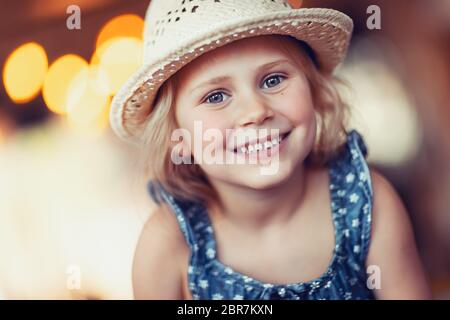 Portrait of nice little smiling girl wearing straw sun hat, enjoying sunny summer holidays, happy healthy childhood Stock Photo