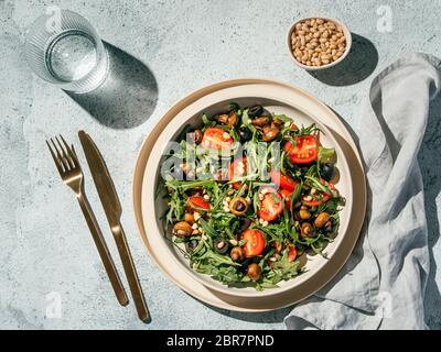 Salad with arugula, mini champignons, cherry tomatoes, black olives, pine nuts. Top view or flat lay. Copy space. Hard light. Horizontal Stock Photo