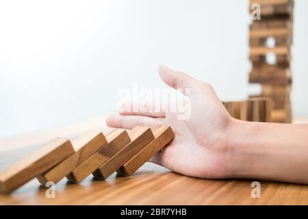 businessman hand stop dominoes continuous toppled or risk with copyspace Stock Photo