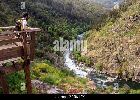 Arouca, Portugal - April 28, 2019: Landscape of the Paiva River with a young man with a backpack watching from the viewpoint on the Paiva Walkways. Stock Photo