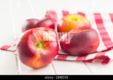 Ripe flat nectarines on white table. Stock Photo