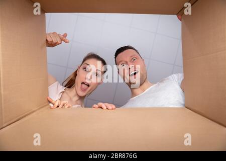 Low Section View Of A Young Happy Couple Looking Inside Cardboard Box Stock Photo