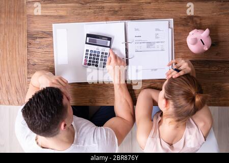 Stressed Young Couple Looking At Invoice On Wooden Desk Stock Photo