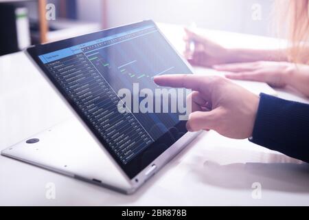 Close-up Businessman's Hand Showing Gantt Chart On Laptop Screen Over White Desk In Office Stock Photo