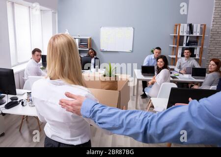 Smiling Young Manager Welcoming New Female Employee Introducing Her To Old Colleagues At Workplace Stock Photo