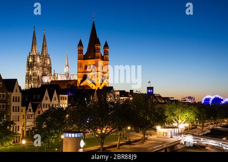 Illuminated towers of Great Saint Martin Church and Cologne Cathedral at night Stock Photo